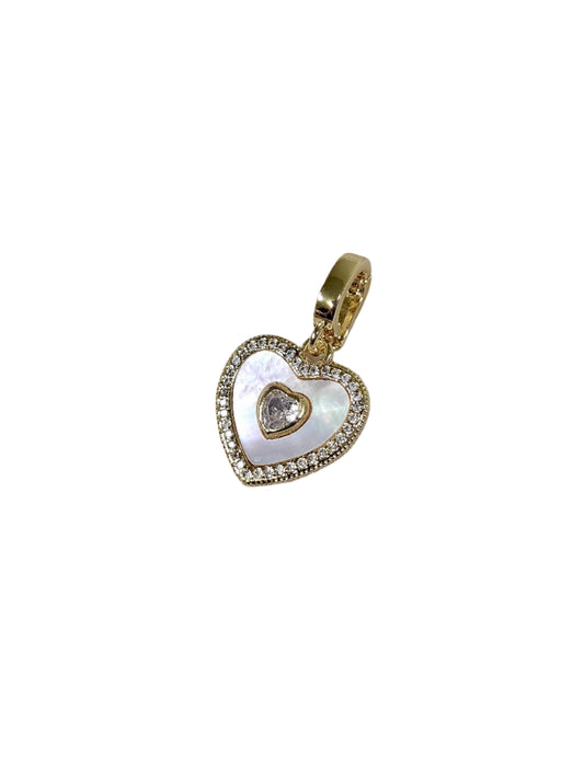 Heart-shaped pendant with gold border and central gemstone on a marble surface